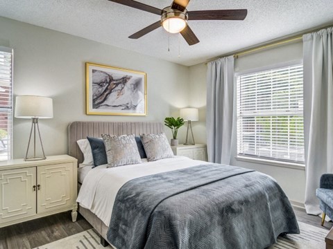 A bedroom with a large bed and a ceiling fan.