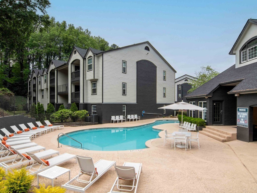 a swimming pool with chairs around it in front of a building