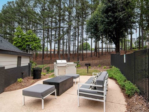 a patio with a grill and a table and benches