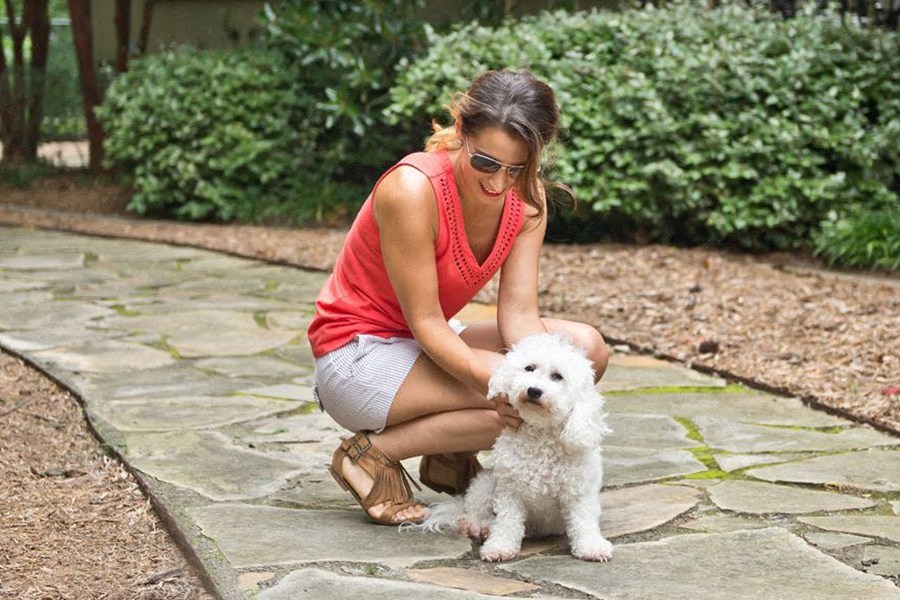 a woman is petting a white dog on the ground