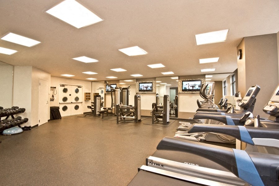a gym with cardio equipment and weights on the floor
