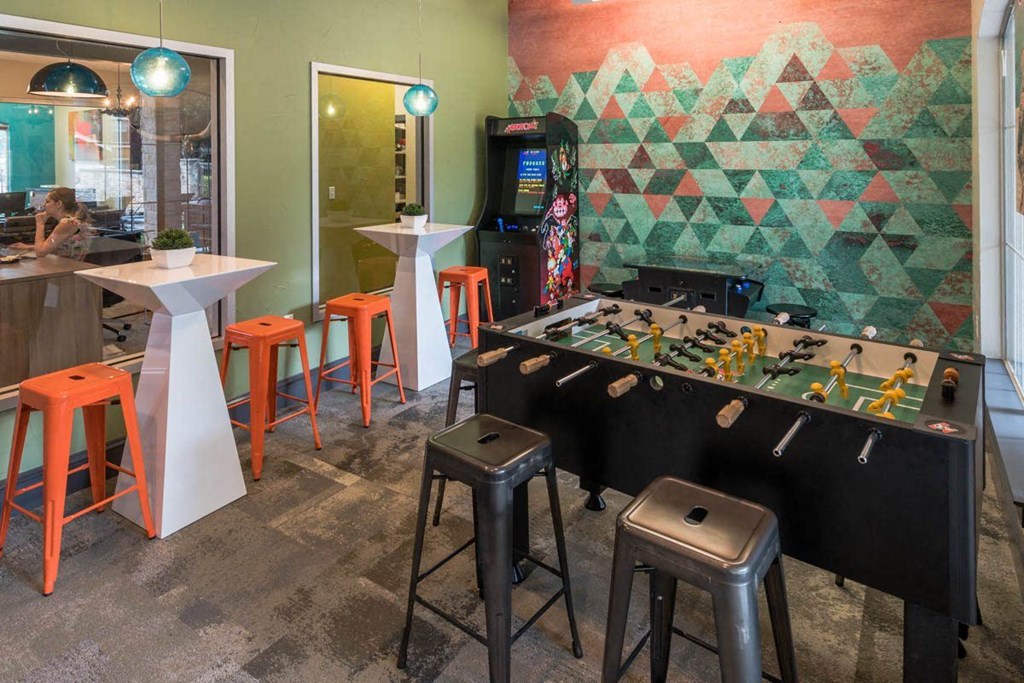 a game room with a foosball table and a 1960s arcade game