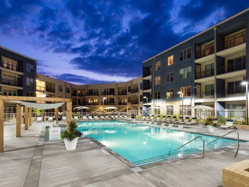 A large swimming pool surrounded by apartment buildings at dusk.