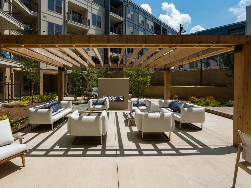 A patio with white chairs and a wooden pergola.