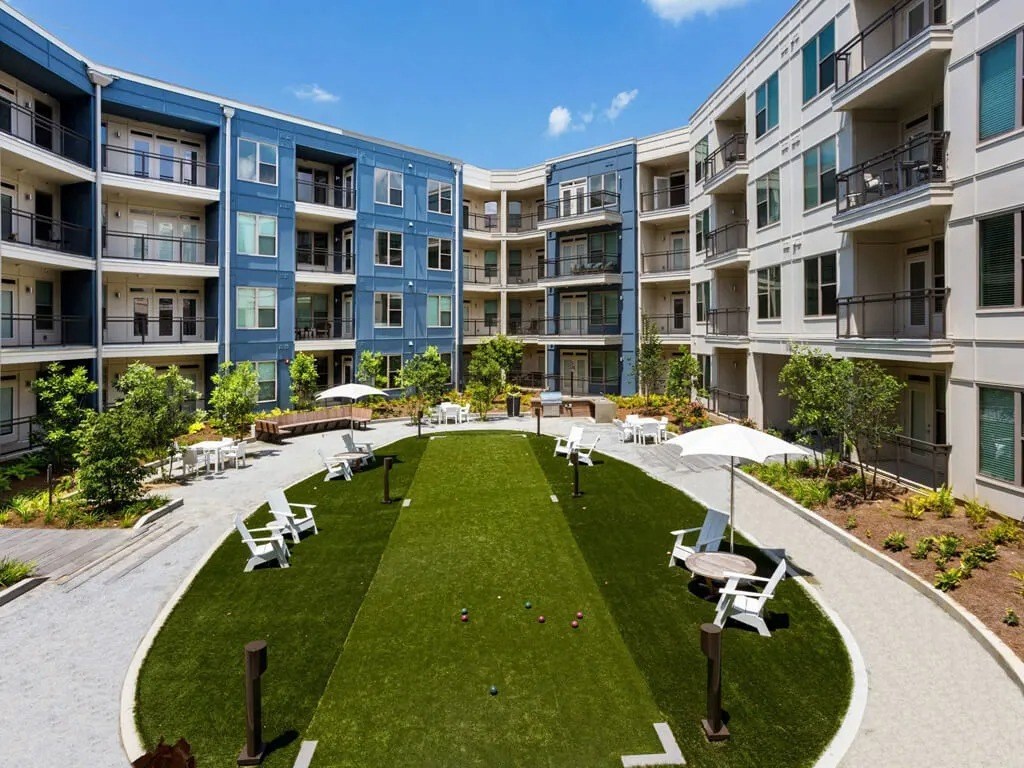 A sunny day at a grassy courtyard surrounded by apartment buildings.