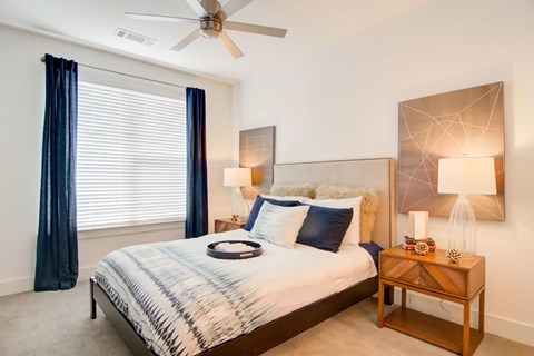 A bedroom with a bed, nightstand, and a ceiling fan.