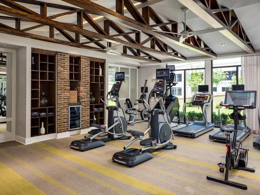 A gym with a variety of exercise equipment including treadmills, stationary bikes, and elliptical machines.