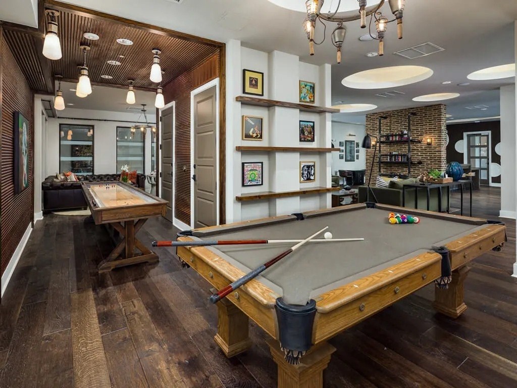 A pool table in a room with a wooden floor and a brick wall.