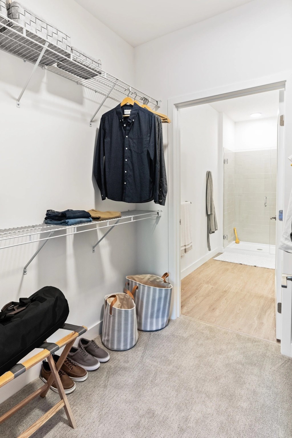 A room with a coat hanging on a rack and a pair of shoes on the floor.