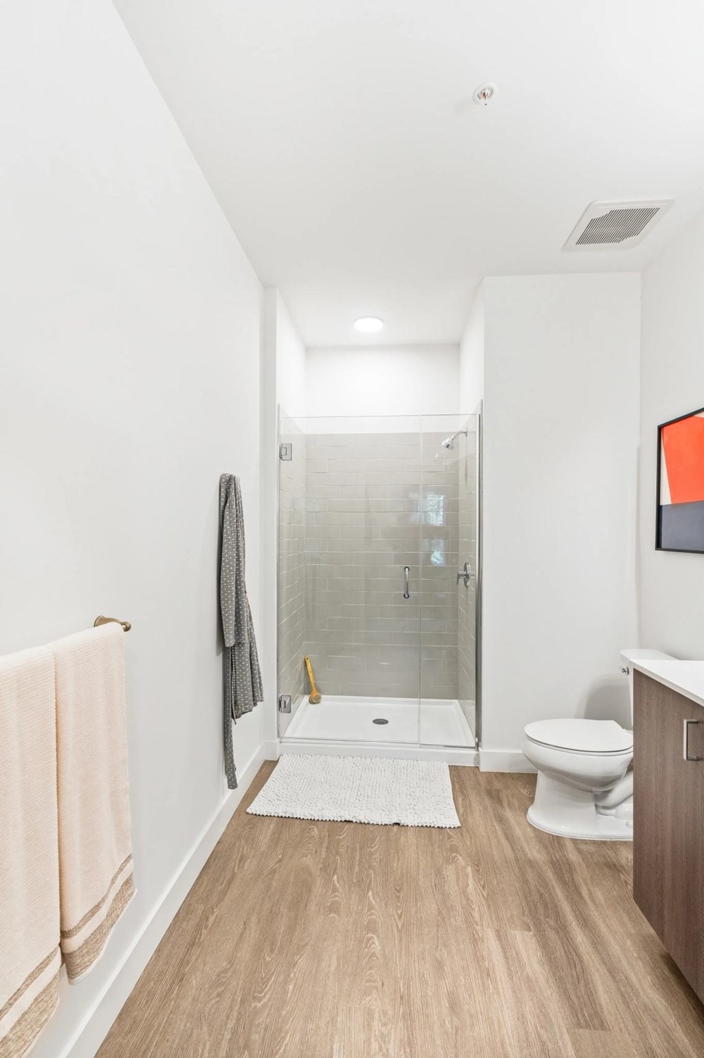 A bathroom with a toilet, a sink, a towel, and a glass shower stall.
