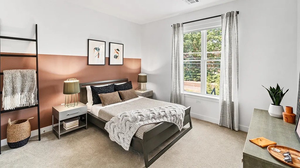 A bedroom with a large bed and a window with curtains.