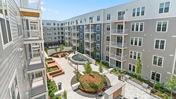 A courtyard surrounded by apartment buildings with a fountain in the middle.