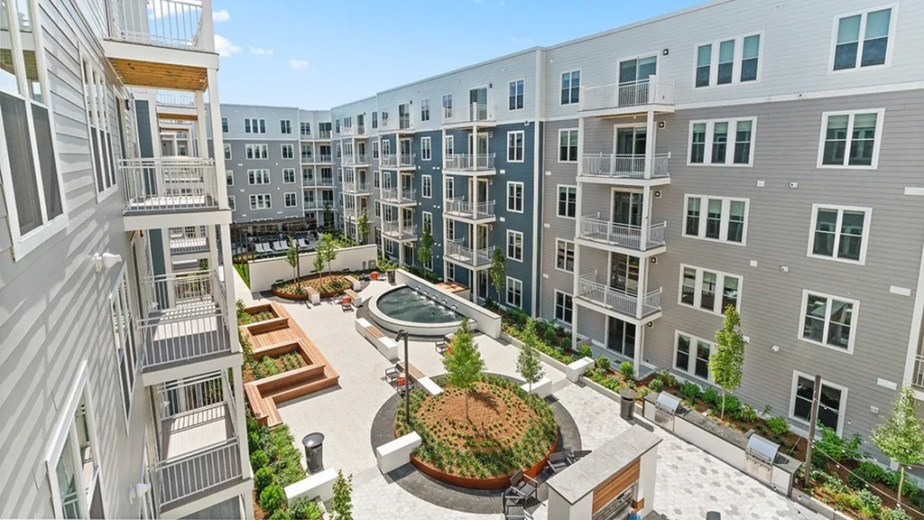 A courtyard surrounded by apartment buildings with a fountain in the middle.