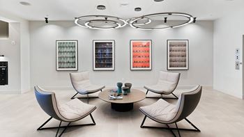 A modern living room with a circular light fixture and a collection of chairs and tables.