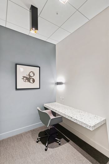 A room with a grey wall and a framed picture hanging on it.