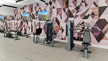 A gym with a variety of equipment including a leg press machine and a rowing machine.