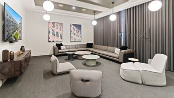 A modern living room with a grey sofa, two grey armchairs, a coffee table, and a wooden sideboard.
