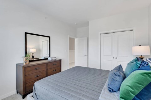 A bedroom with a bed, dresser, and mirror.