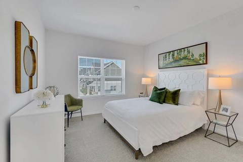 A bedroom with a large bed, a chair, and a painting on the wall.