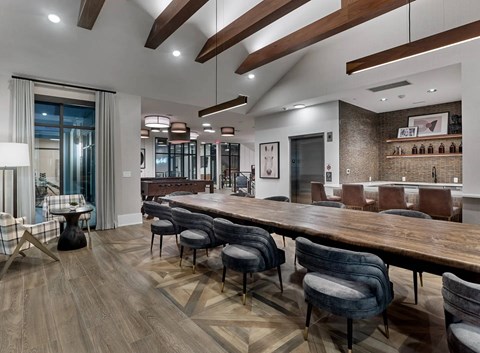 A modern dining room with a long wooden table and chairs.