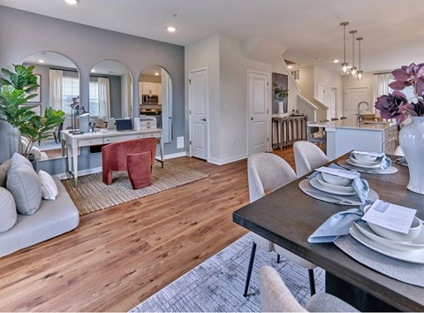A modern dining room with a wooden floor and a large mirror on the wall.