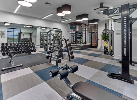 A gym with a variety of equipment including dumbbells, weight plates, and a squat rack.