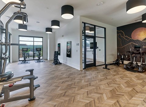 A gym with a variety of equipment including a treadmill, weights, and a bench press.