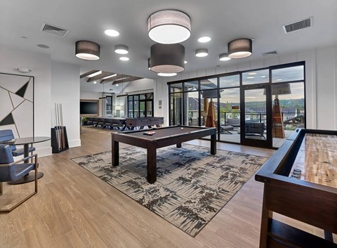 A modern living room with a pool table and a view of the outdoors.