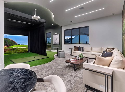 A modern living room with a large window and a golf simulator.