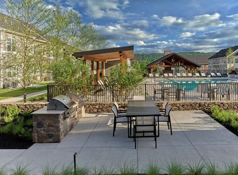 A patio with a table and chairs overlooking a pool.