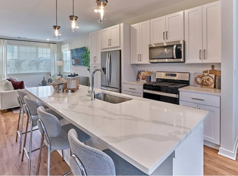 A kitchen with a white countertop and grey chairs.