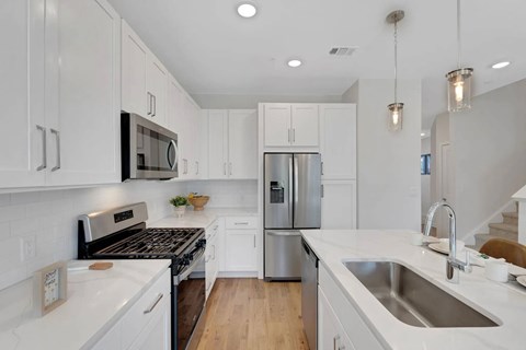 A modern kitchen with white cabinets and stainless steel appliances.