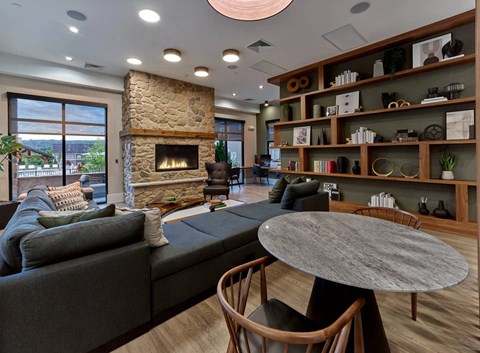 A modern living room with a stone fireplace and a large grey sofa.