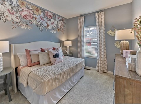 A bedroom with a large bed and a floral wall mural.