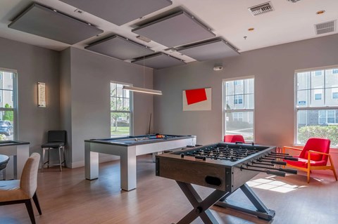 A room with a pool table and a foosball table.