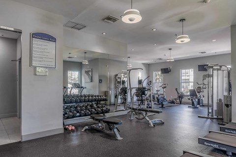 A gym with a variety of equipment including treadmills, weights, and exercise machines.