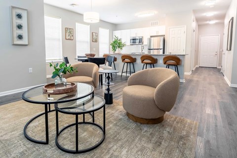 A modern living room with a glass table and two chairs.