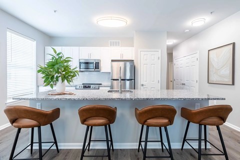 A kitchen with a bar area featuring three brown barstools.