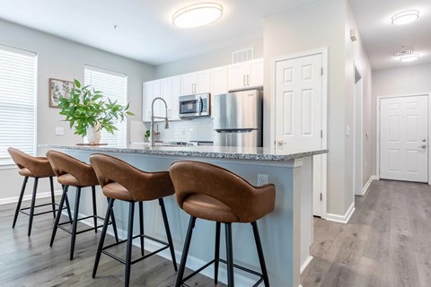 A kitchen with a bar area and chairs.