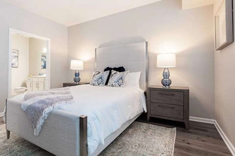 A bedroom with a large bed and two lamps on the nightstand.