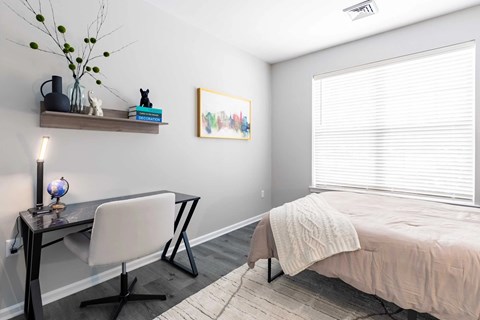 A bedroom with a bed, desk, and chair.
