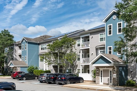 A row of townhouses with cars parked in front.