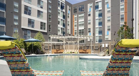 A pool area with a water slide and two lounge chairs.