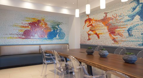 A dining room with a large mosaic on the wall and a wooden table with chairs.