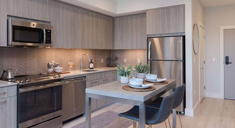 A modern kitchen with a dining table set for two.