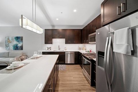 A modern kitchen with dark wood cabinets and stainless steel appliances.