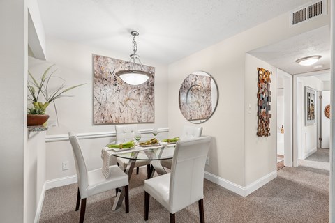A dining room with a table set for two and a large abstract painting on the wall.
