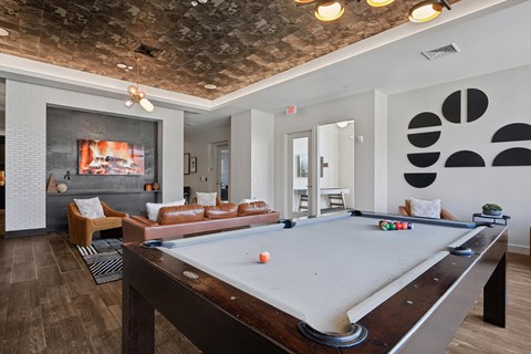 A pool table is in the middle of a room with a couch and a television.