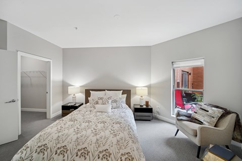 A bedroom with a large bed and a chair.