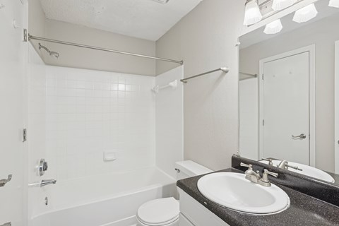A white bathroom with a toilet, sink, and shower.